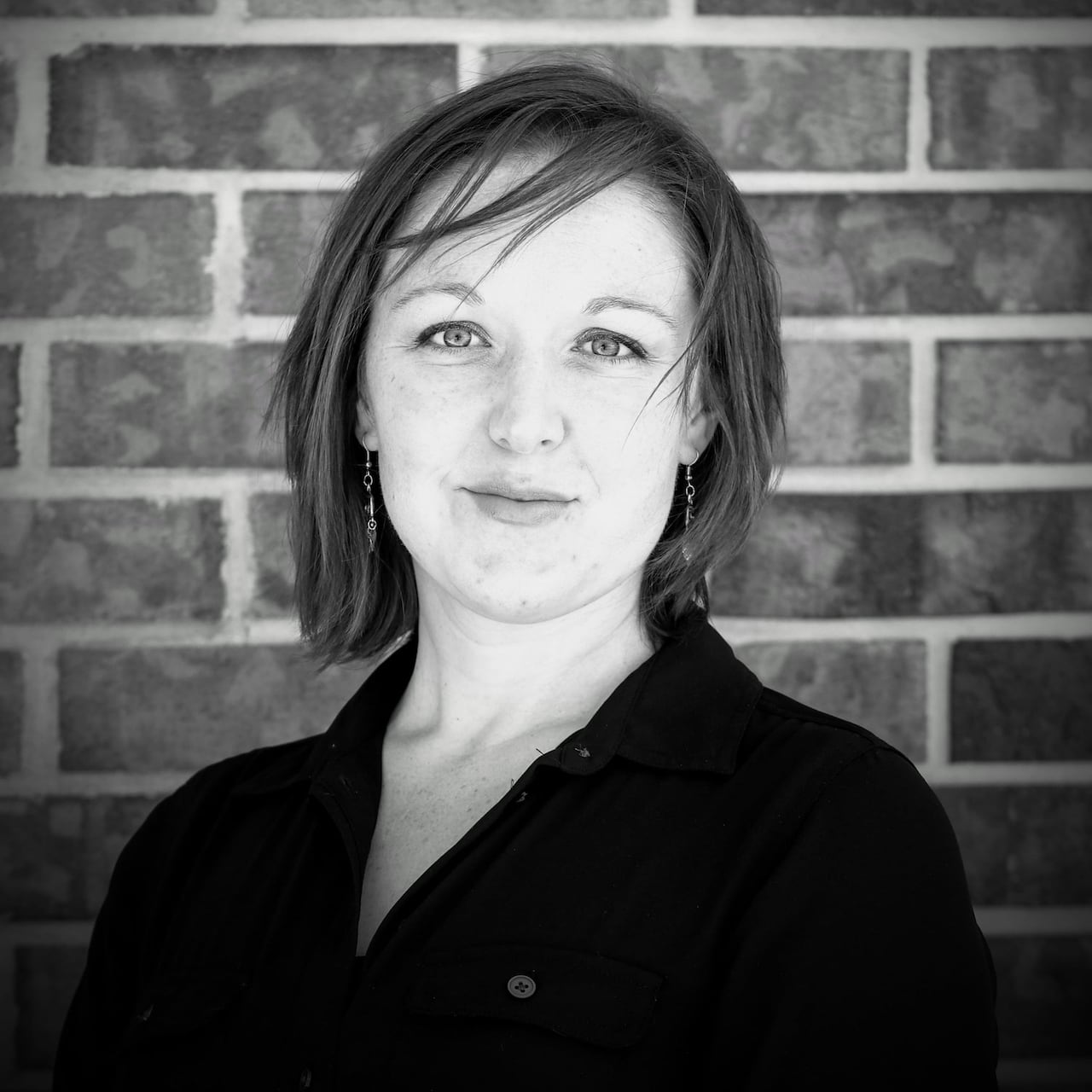 A woman with short hair with bangs and an androgynous expression.