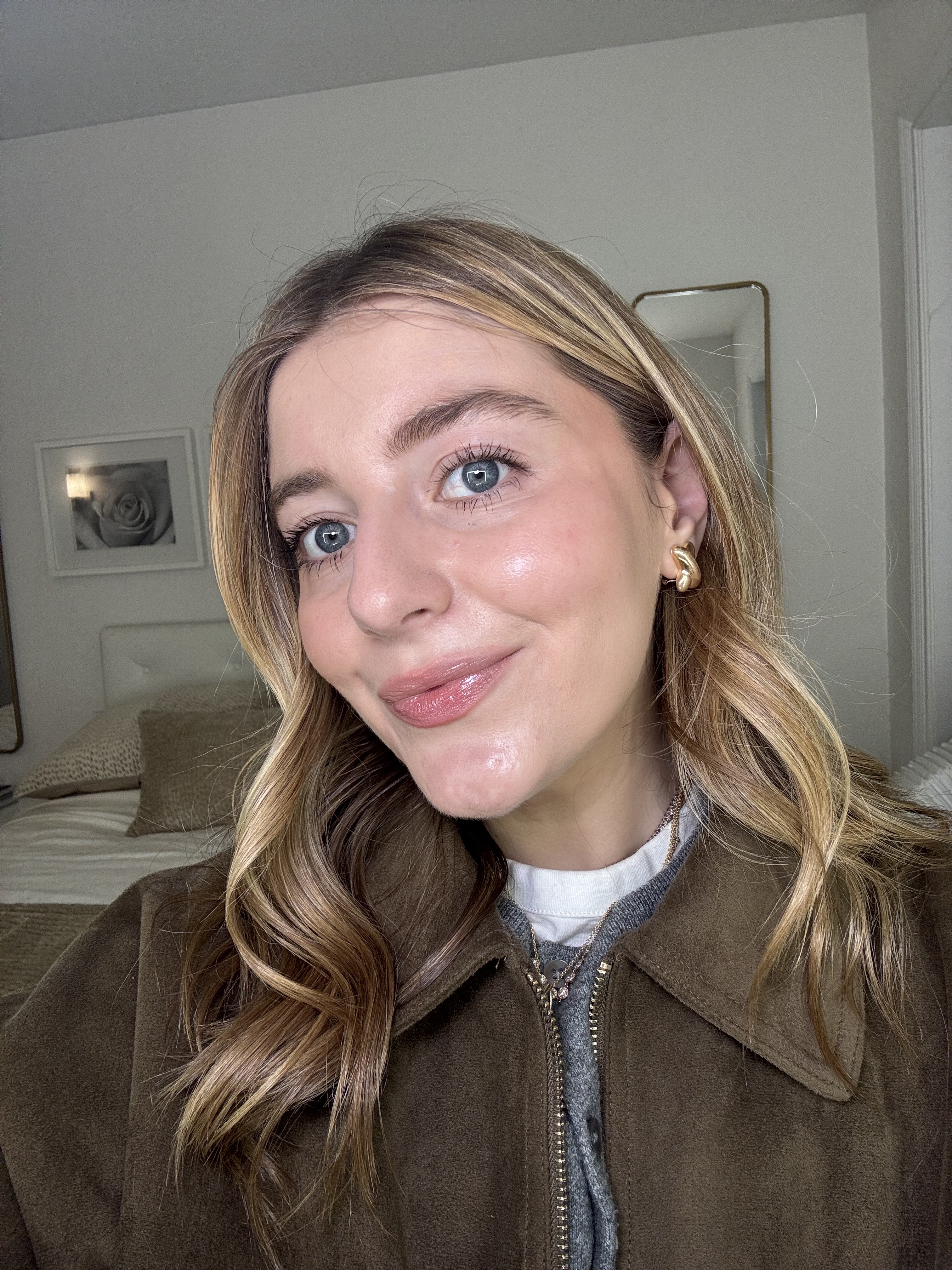 Woman with blonde hair and glowing skin in a brown jacket