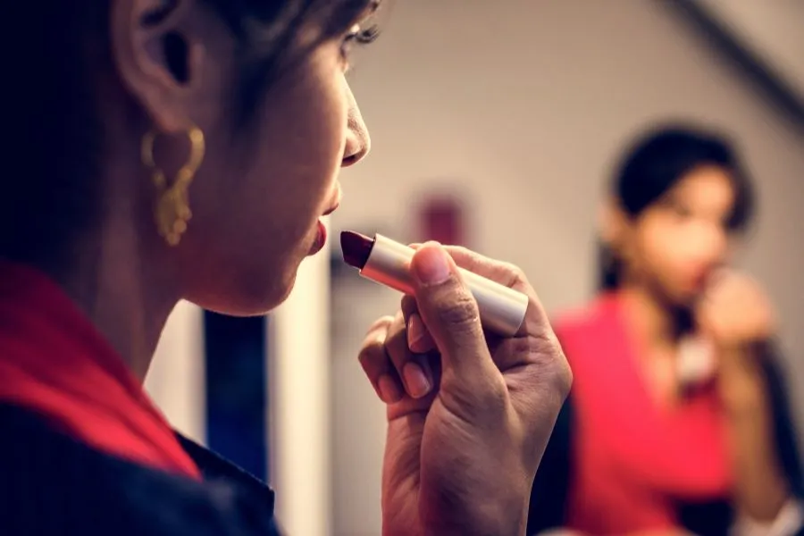 Woman applying lipstick in the mirror