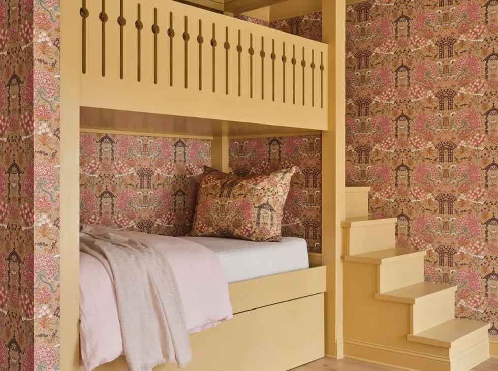 Yellow bunk beds, stairs, floral wallpaper and pink bedding.