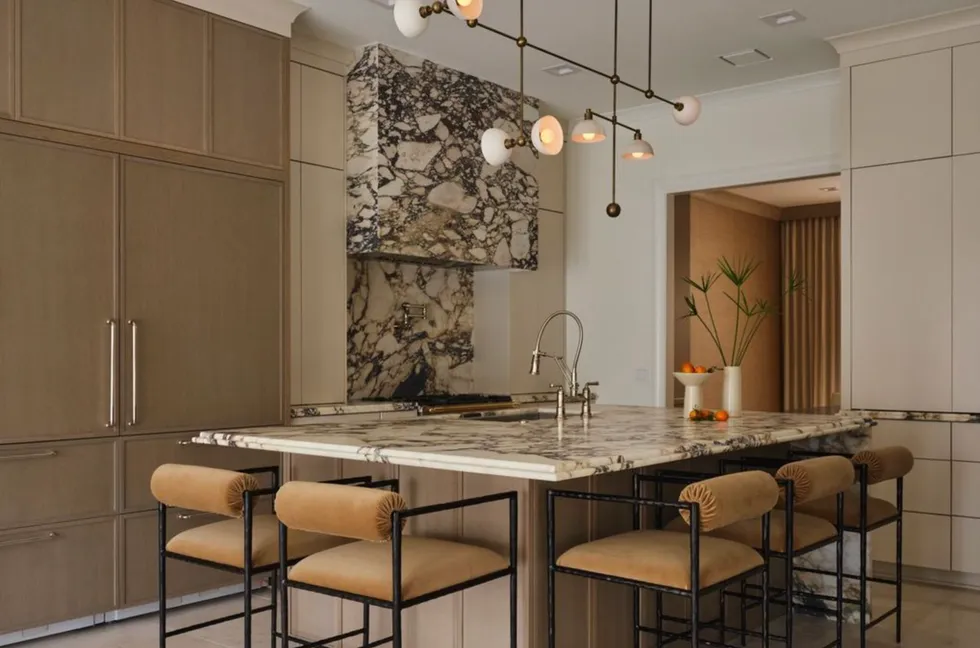 Modern kitchen with marble accents, island seating, and unique pendant lighting.