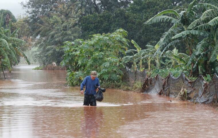 JAMM AQUINO / JAQUINO@STARADVERTISER.COM A man walks through floodwaters on Kaupe Street in Waialua on March 20. The Hawaii Department of Health and the Hawaii Humane Society are asking residents and recovery workers to monitor for signs of leptospirosis in the wake of Kona Depression's storm surge flooding.
