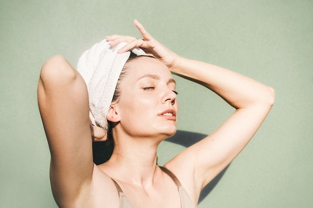 woman with hair towel and fresh clean skin against green background